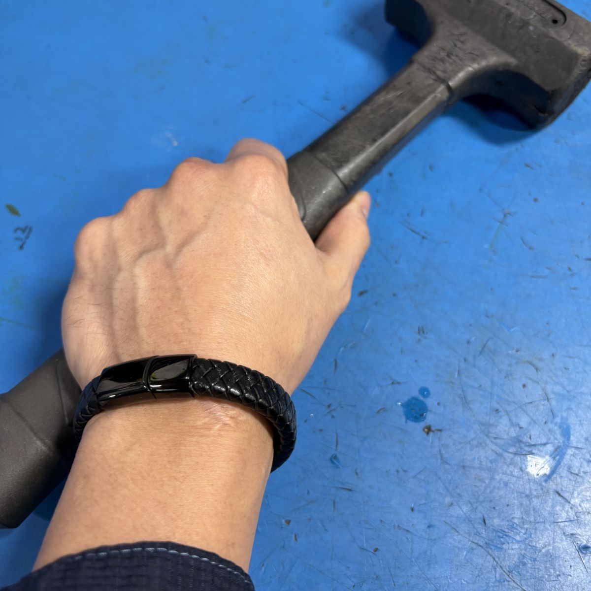 Wearing a black leather bracelet holding a hammer