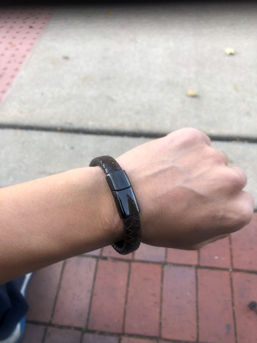 Person wearing a black smartwatch on a wrist with a blurred background
