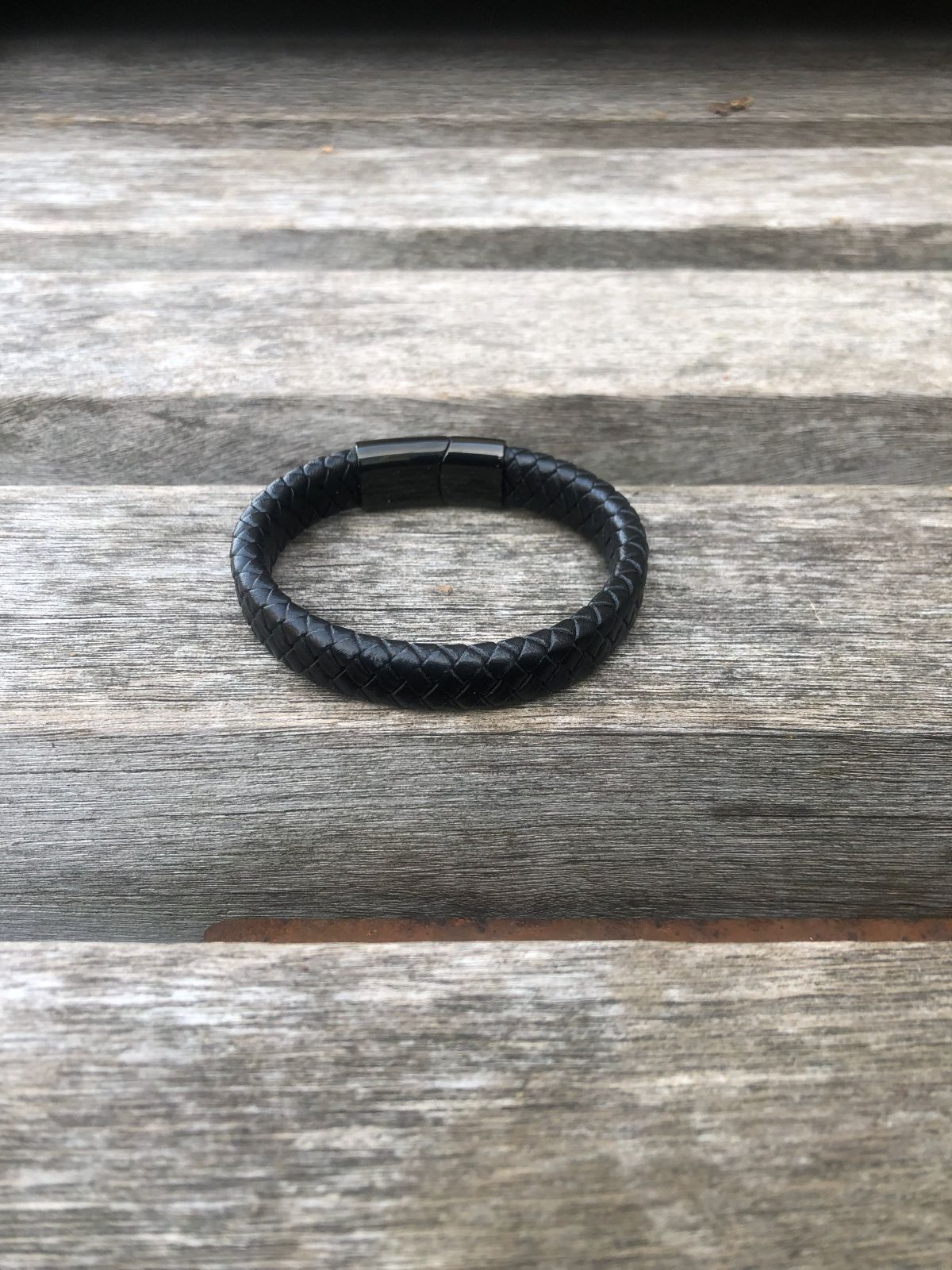 Black leather bracelet on a wooden surface