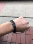 Person wearing a black smartwatch on a wrist with a sidewalk background