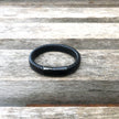 Black braided leather bracelet on a wooden surface