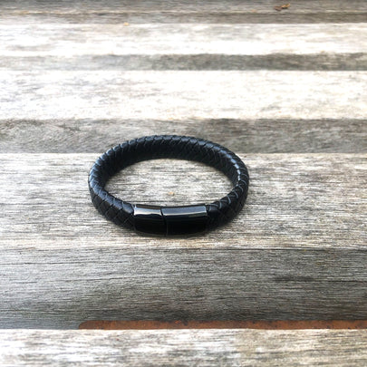 Black braided leather bracelet on a wooden surface