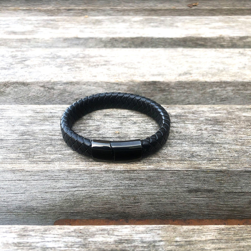 Black braided leather bracelet on a wooden surface