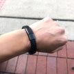 Black braided bracelet on a wrist with a blurred background