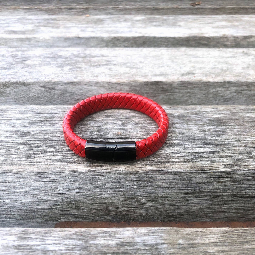 Red braided leather bracelet with a black magnetic clasp on a wooden surface