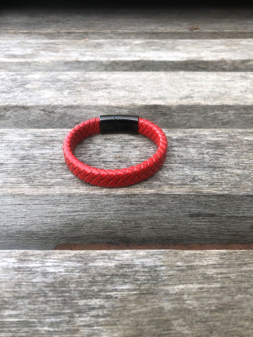 Red bracelet with a black clasp on a wooden surface