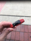 Red textured USB drive held in a hand with a blurred background