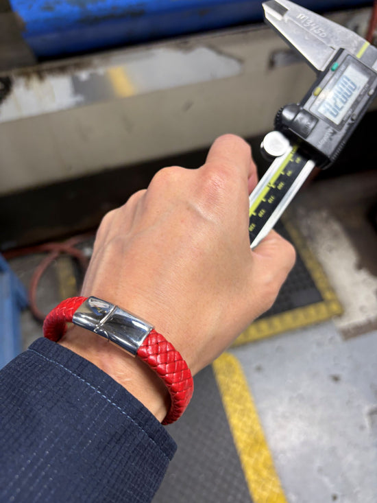 Hand with red wristband using digital caliper on a blurred background