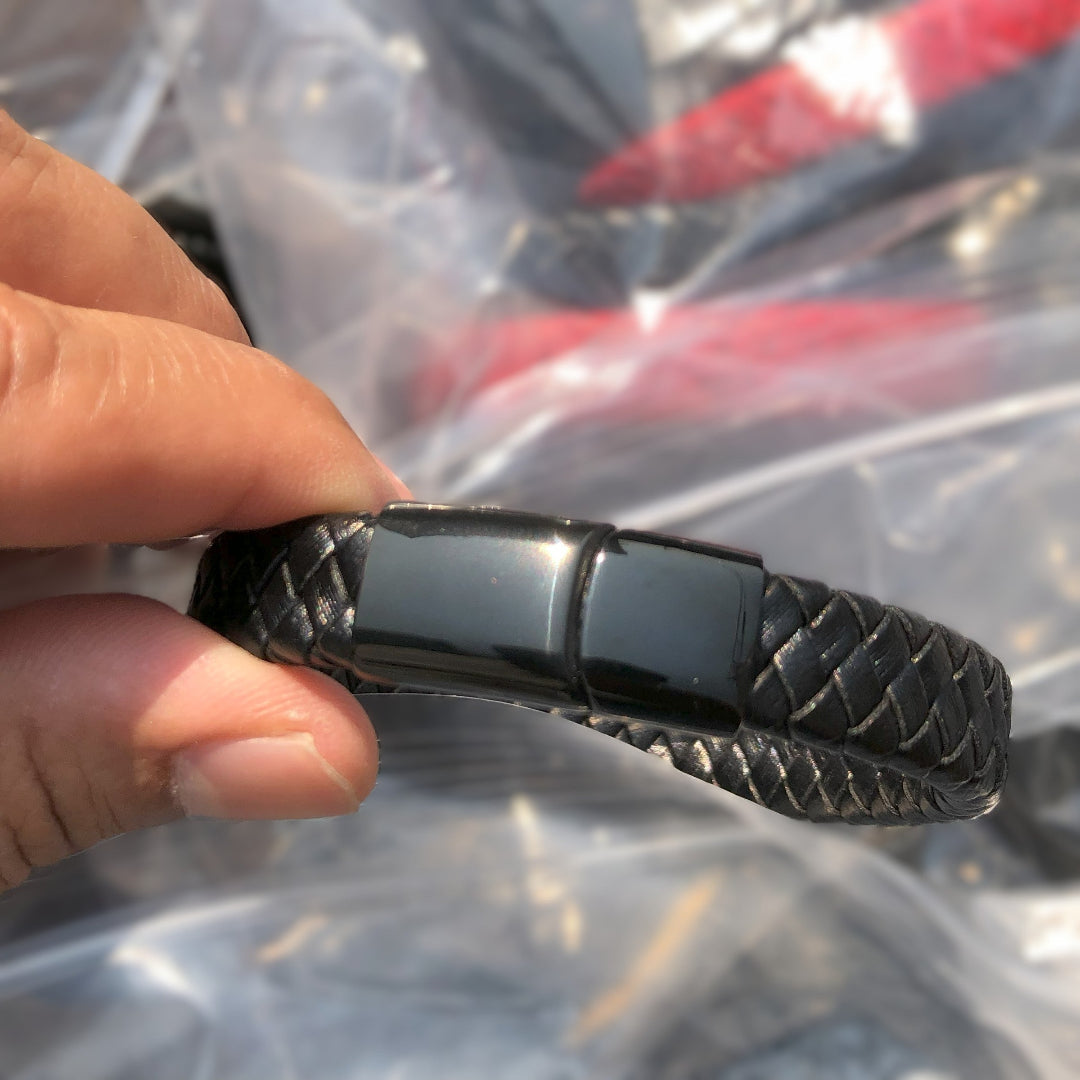 Black braided bracelet held by a hand against a transparent background