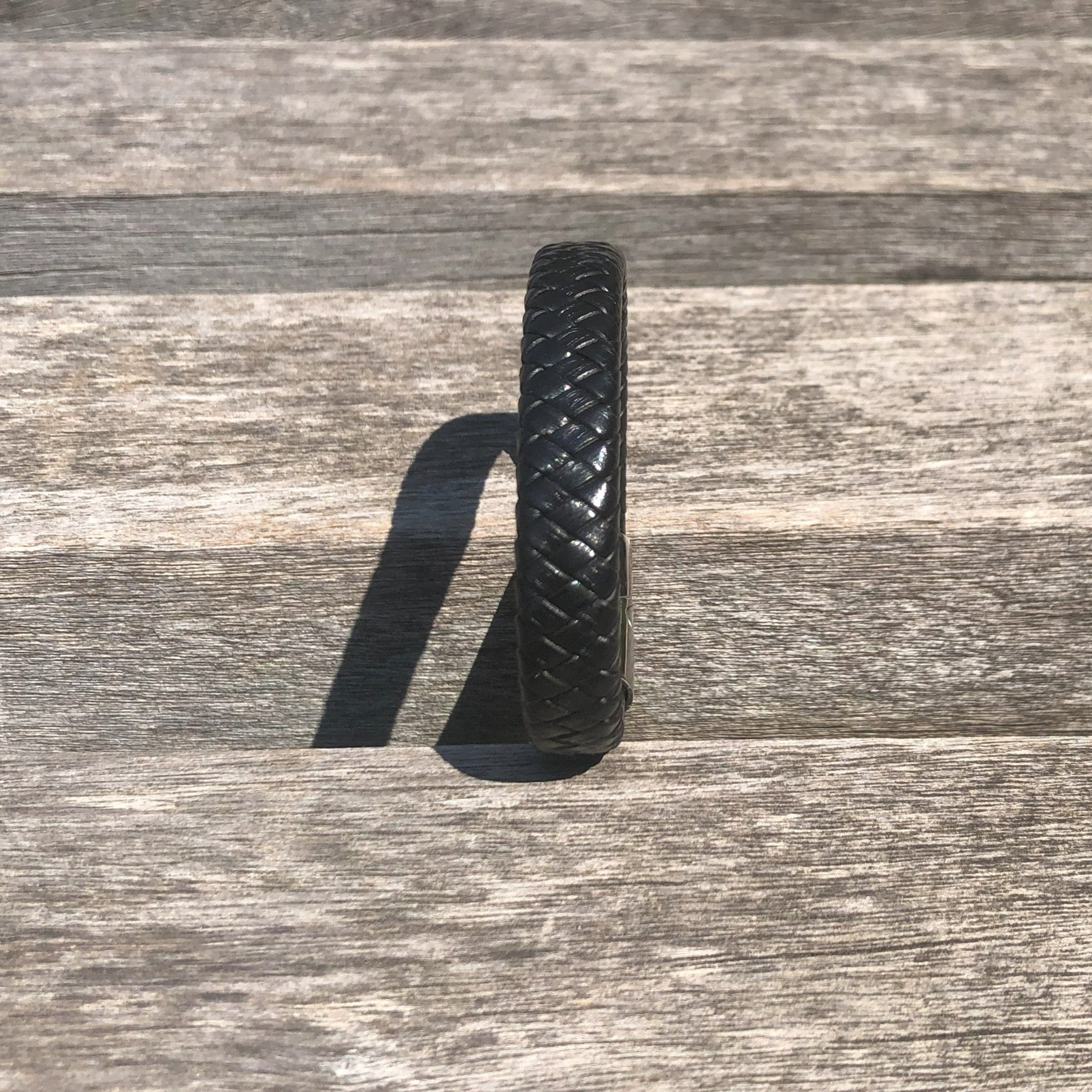 Black woven bracelet on a wooden surface