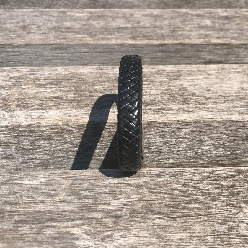 Black woven bracelet on a wooden surface