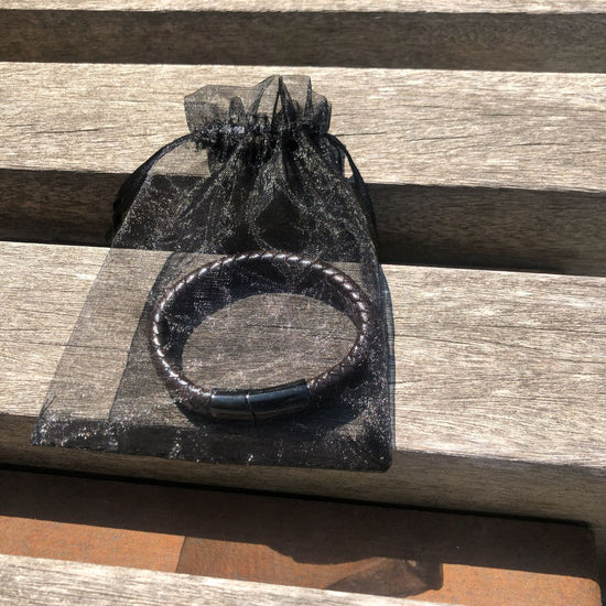 Black beaded bracelet in a clear drawstring bag on a wooden surface
