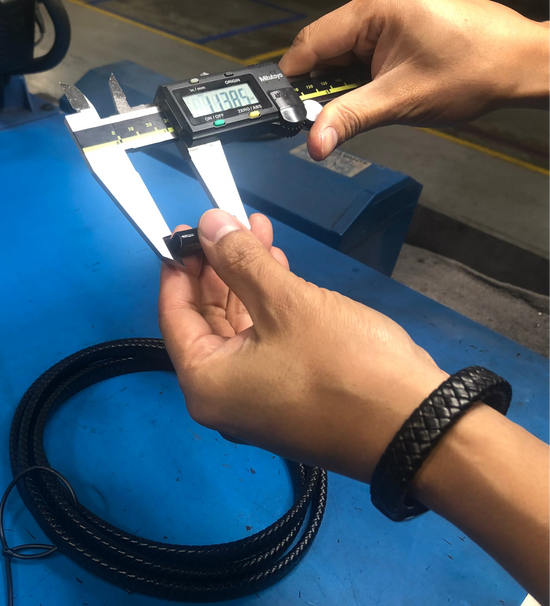 Person using a digital caliper to measure a small object on a blue workbench.