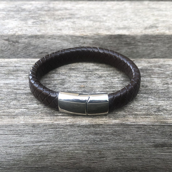Brown leather bracelet with a silver clasp on a wooden surface
