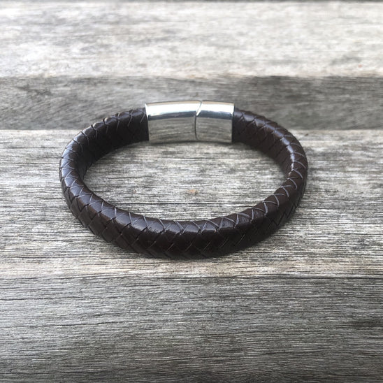 Brown leather bracelet with silver clasp on a wooden surface