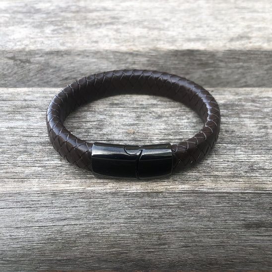 Brown leather bracelet with a black magnetic clasp on a wooden surface