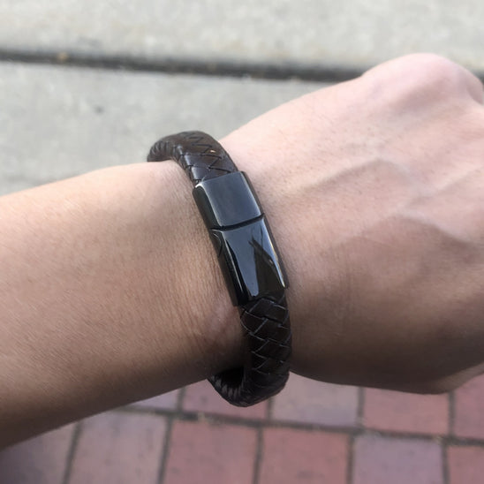 Black braided bracelet on a wrist with a blurred background