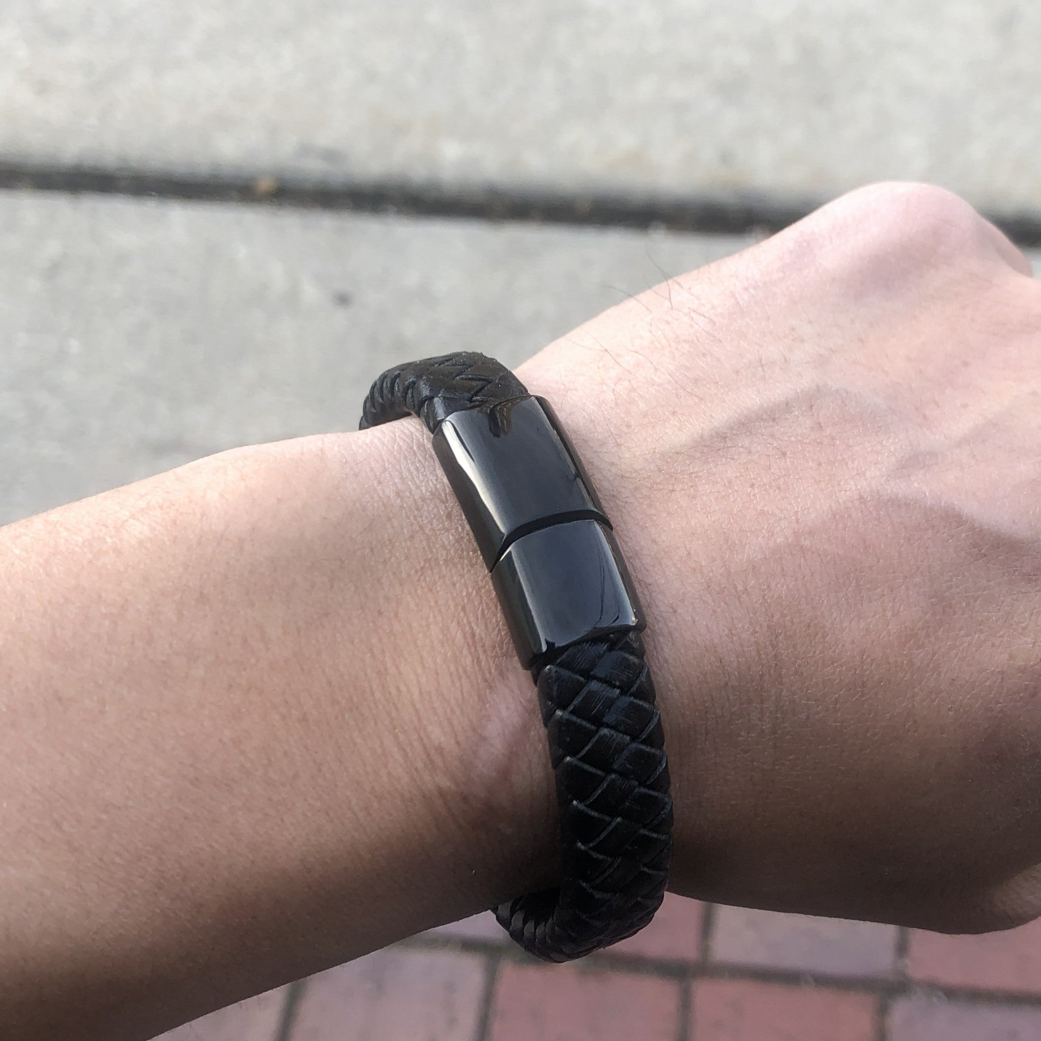 Black braided bracelet on a wrist with a blurred background