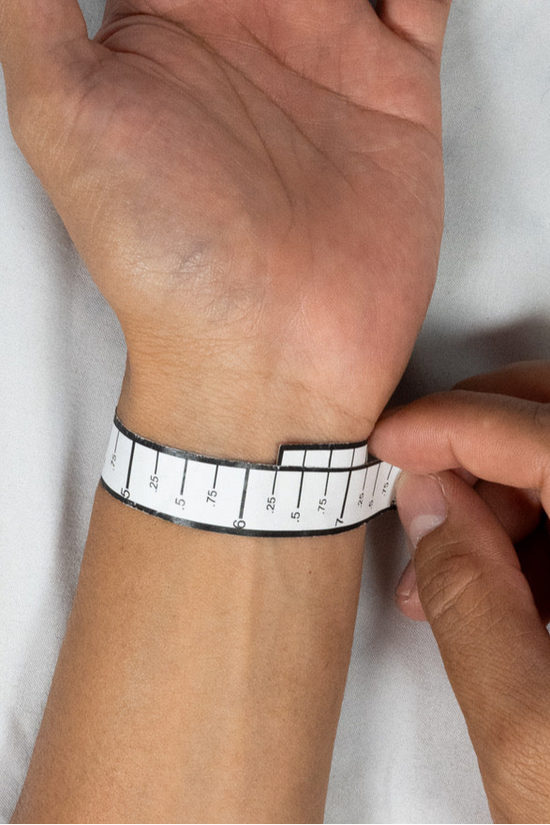 Person measuring wrist with a ruler on a white background