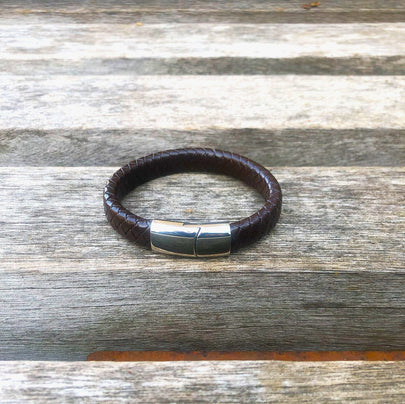 Brown leather bracelet with a silver clasp on a wooden surface