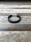 Black leather bracelet with a silver clasp on a wooden surface