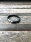 Black leather bracelet with silver clasp on a wooden surface