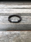 Black leather bracelet with a silver clasp on a wooden surface