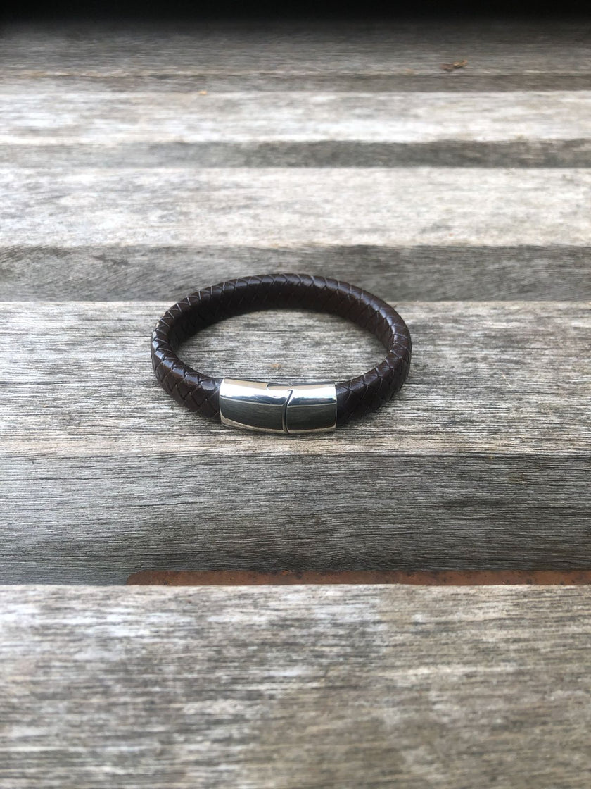 Black leather bracelet with a silver clasp on a wooden surface
