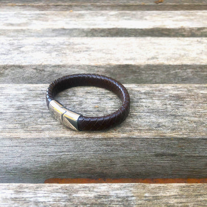 Brown leather bracelet with silver clasp on a wooden surface