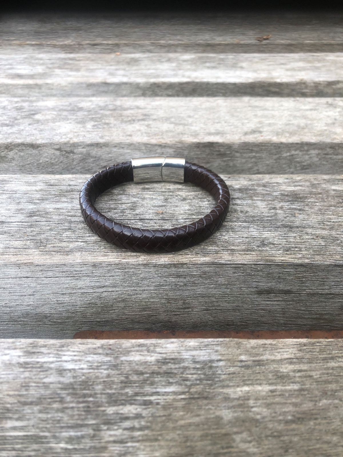 Brown leather bracelet with a silver clasp on a wooden surface