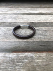 Brown leather bracelet with a silver clasp on a wooden surface
