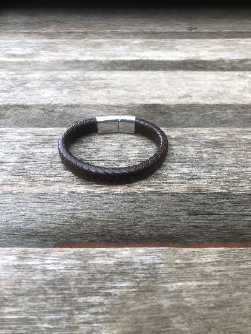 Brown leather bracelet with a silver clasp on a wooden surface