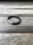 Black leather bracelet with silver clasp on a wooden surface
