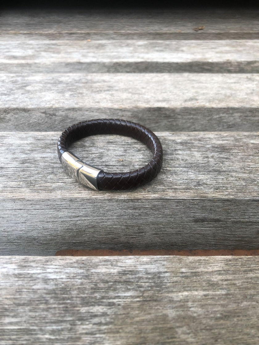 Black leather bracelet with silver clasp on a wooden surface