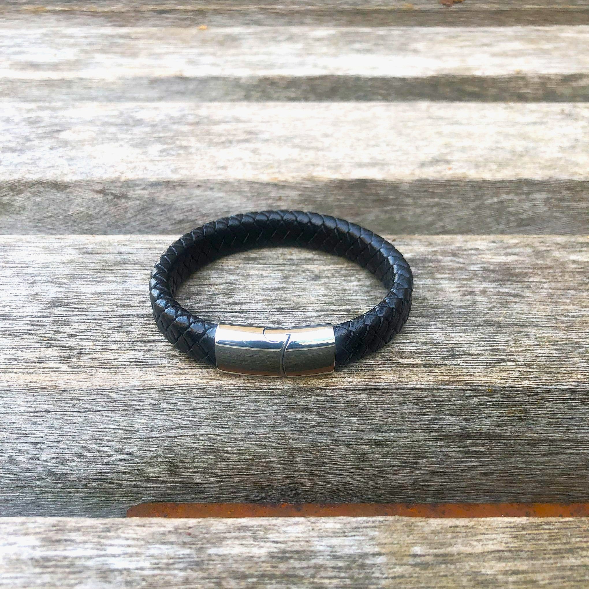 Black leather bracelet with a silver clasp on a wooden surface