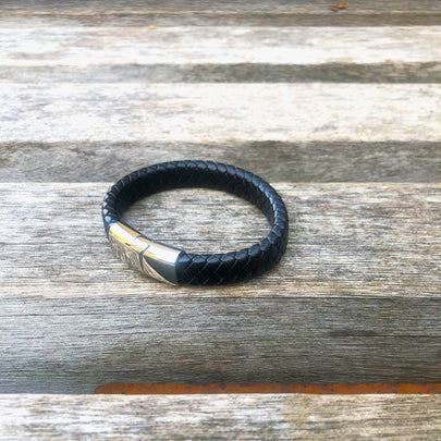 Black leather bracelet with silver clasp on a wooden surface