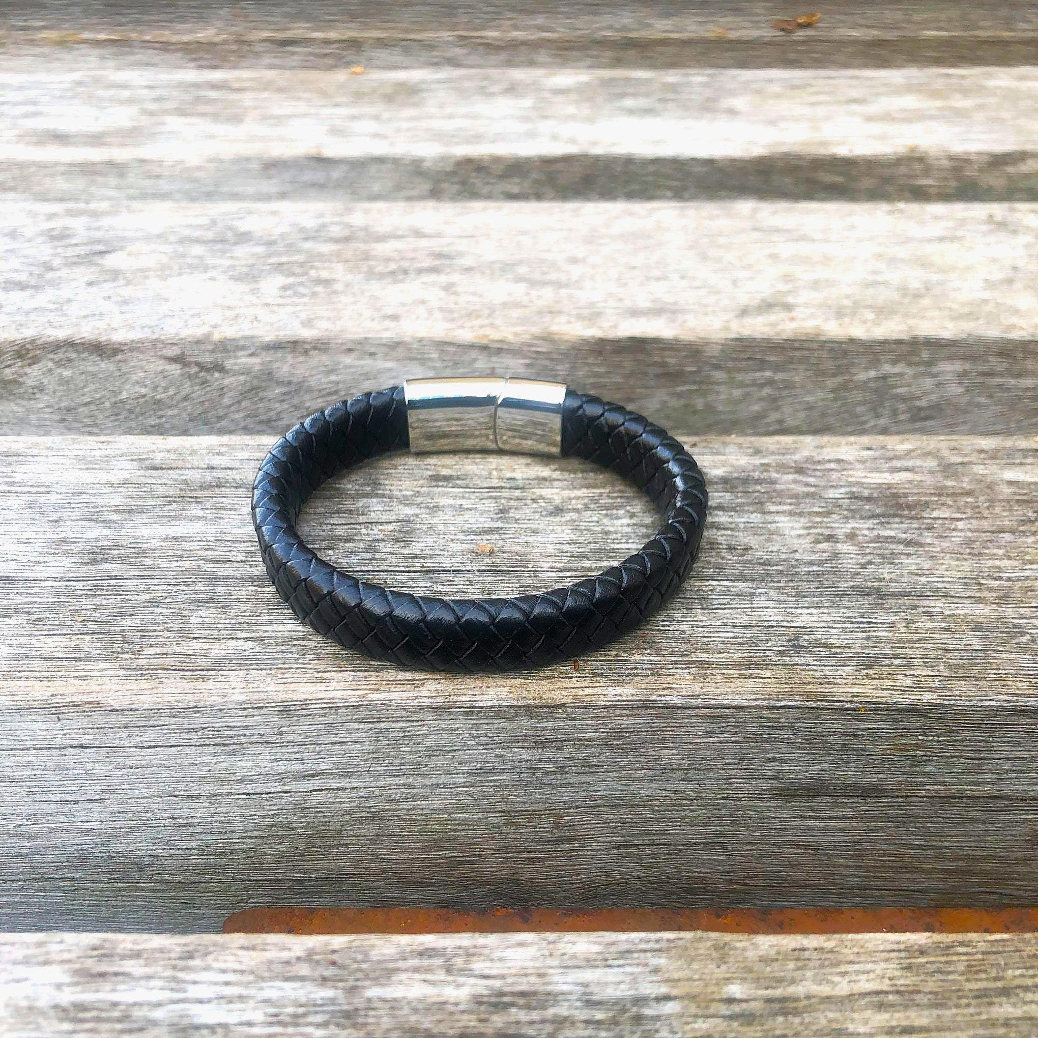 Black leather bracelet with silver clasp on a wooden surface