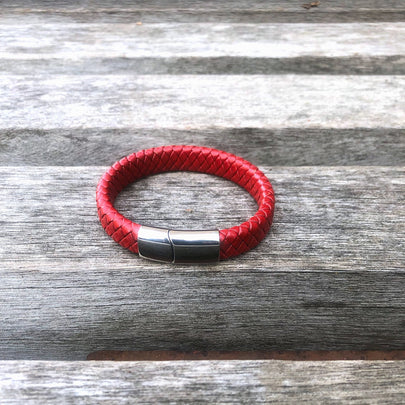 Red braided leather bracelet with a silver clasp on a wooden surface