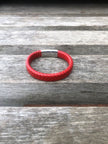 Red braided leather bracelet on a wooden surface