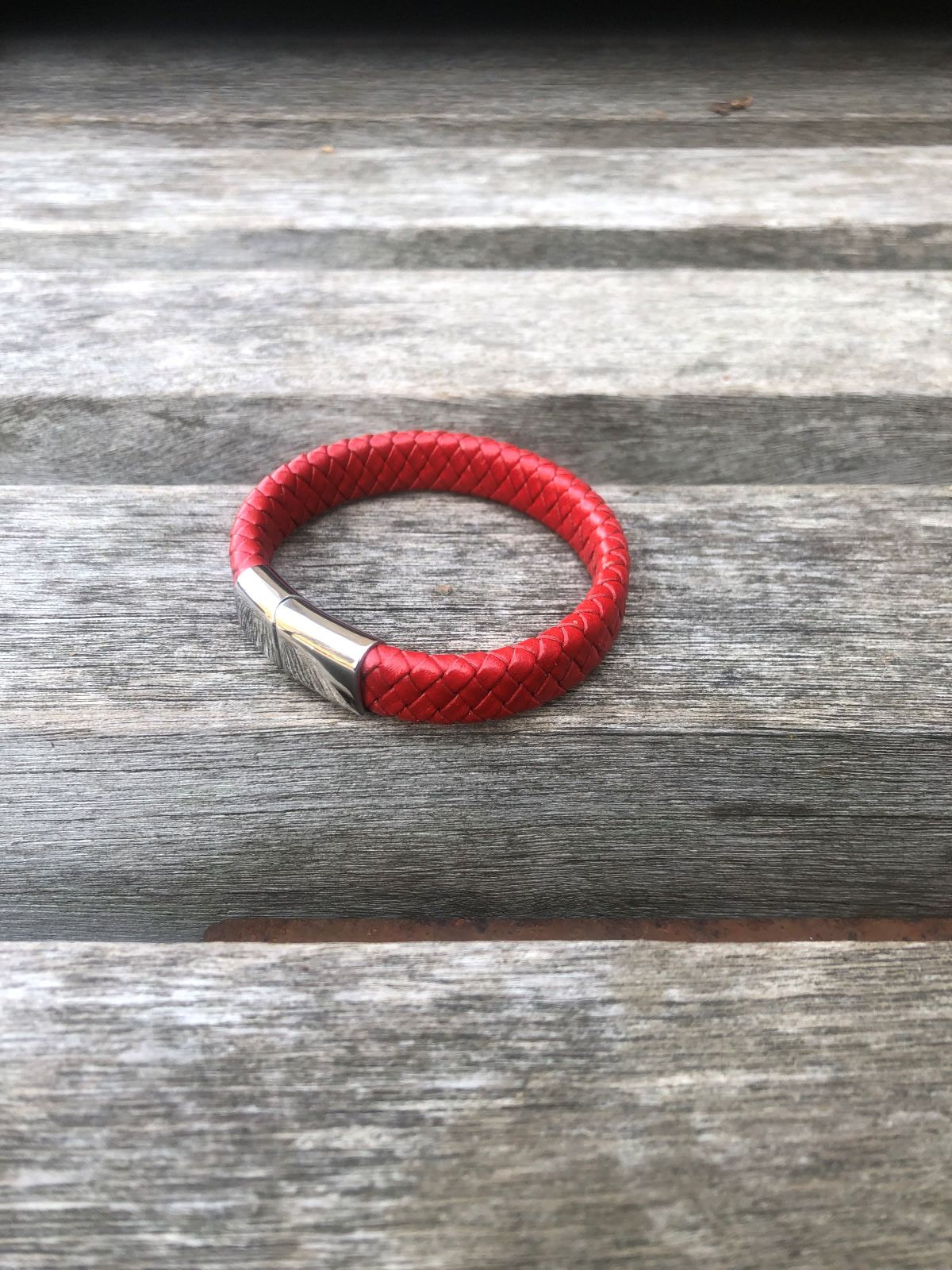 Red braided leather bracelet on a wooden surface