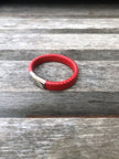 Red braided leather bracelet on a wooden surface