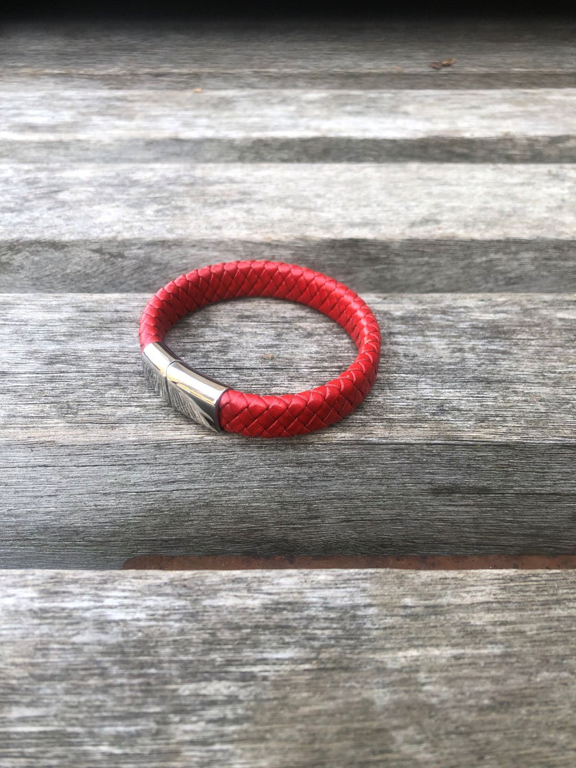 Red braided leather bracelet on a wooden surface