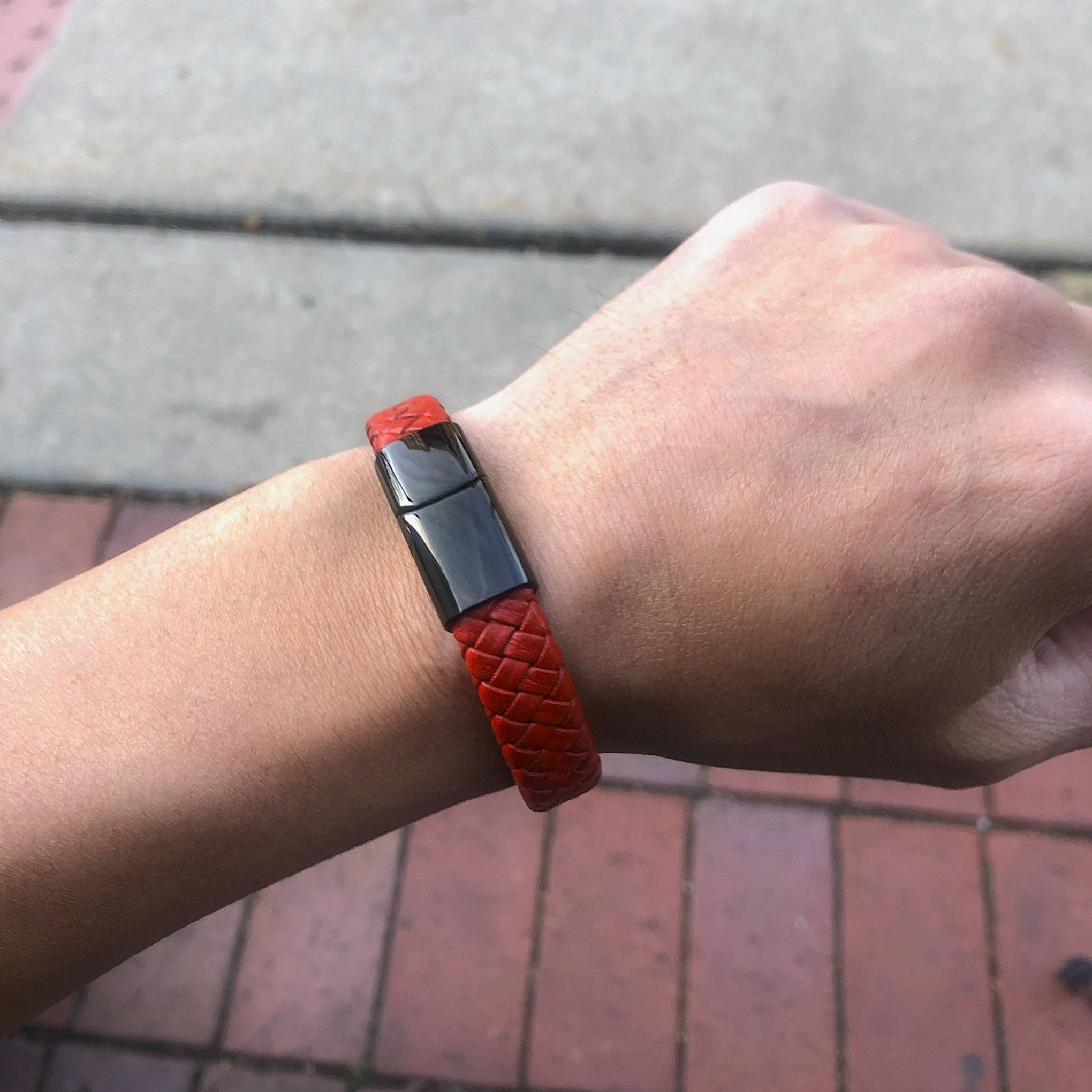 Red wristband with a black buckle on a wrist, blurred background