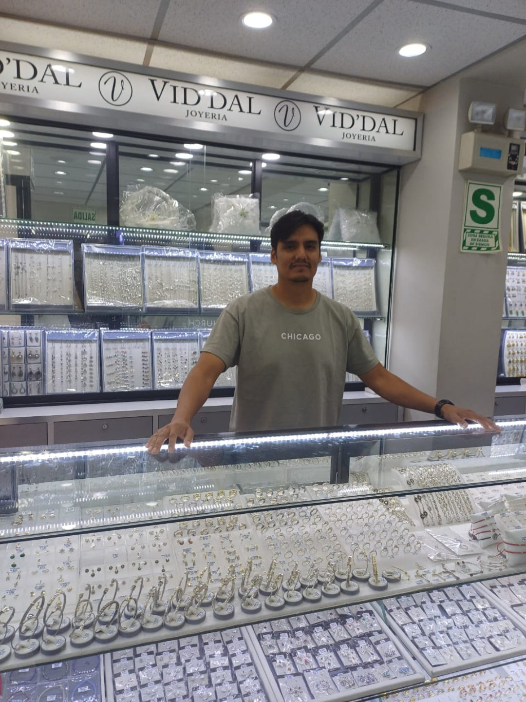 Man standing behind a jewelry display case in a store with 'VID' DAL' branding.
