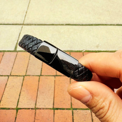 Men’s black braided leather bracelet held in hand