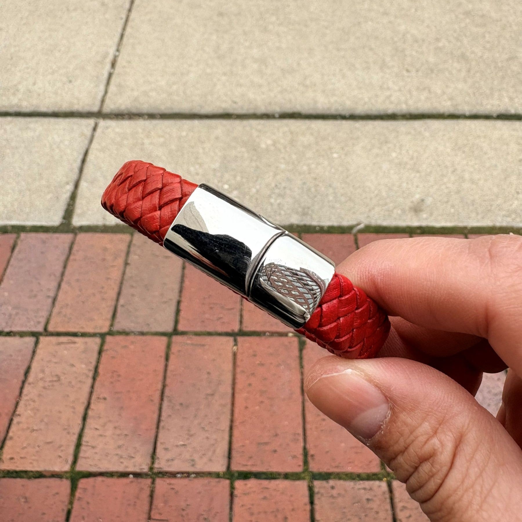 Men’s red braided leather bracelet held in hand